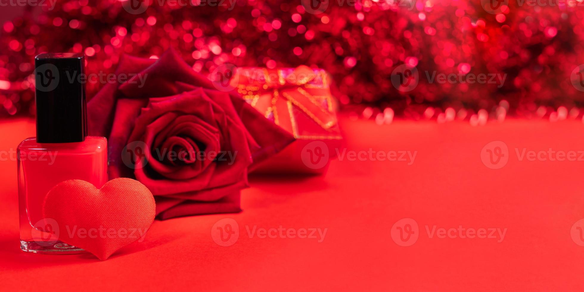 Red Valentines day or mothers day banner. Nail polish, textile heart, rose, gift box on red background with bokeh. photo