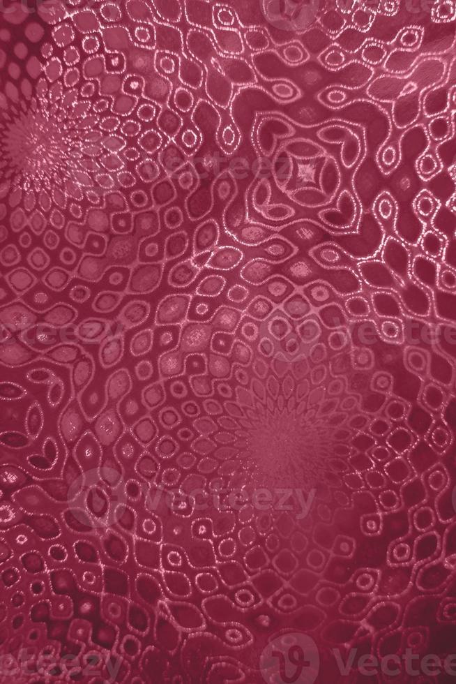 Decorative pattern on textured holographic paper toning in color of 2023 Viva Magenta. Selective focus. photo