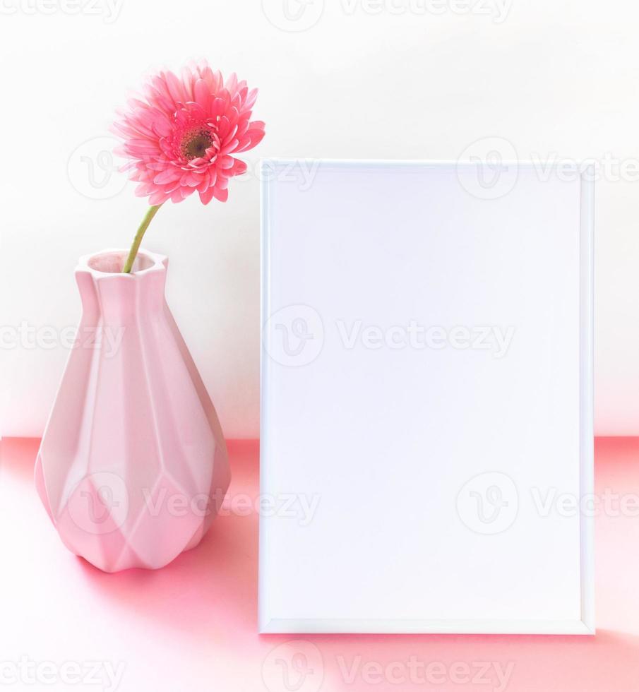 Vase with pink gerbera flower, white empty frame on two tone pink-white. Creative minimal mockup. photo