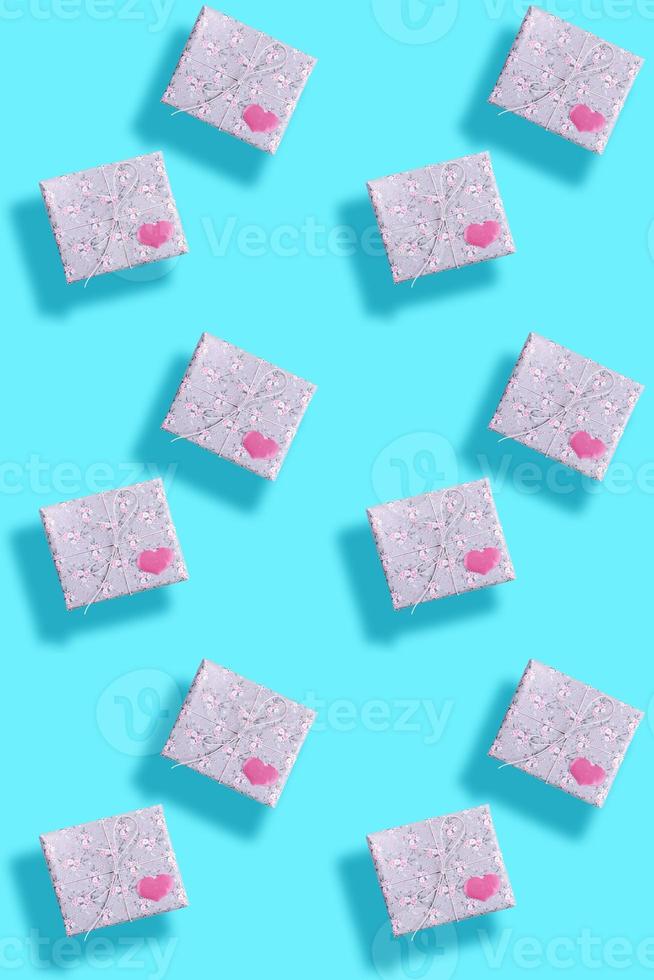 patrón impecable de cajas de regalo, envuelto en papel gris con motivos florales con corazones rosas y sombras en turquesa. foto