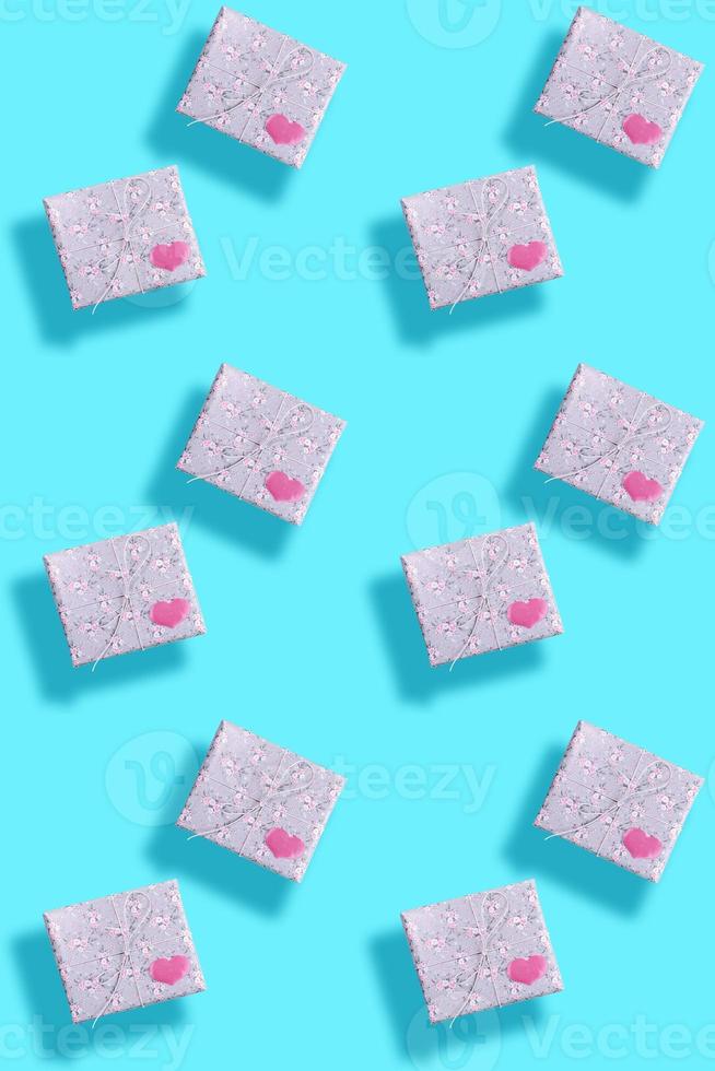 Seamless pattern of gift boxes, wrapped in grey paper with floral pattern with pink hearts and shadows on turquoise. photo