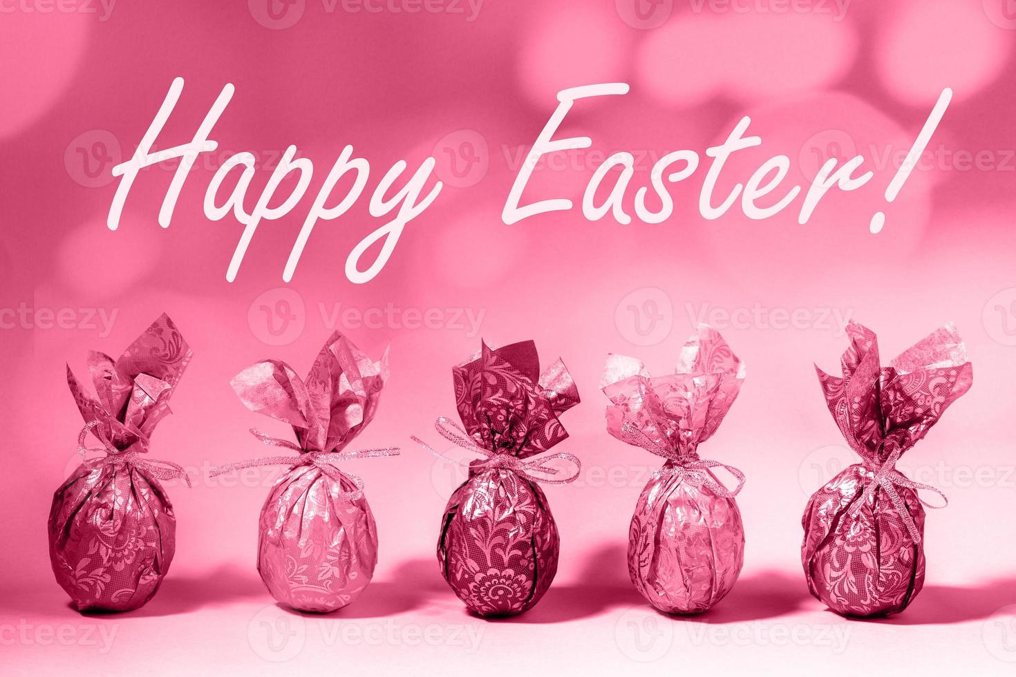 Trendy toned in color 2023 Viva Magenta Easter card with wrapped Easter eggs and words Happy Easter photo