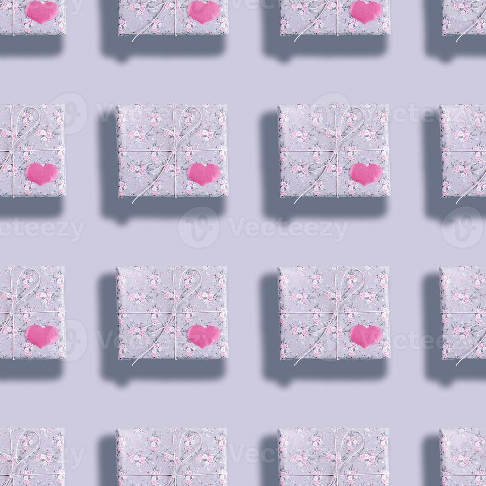 Seamless pattern of gift boxes wrapped in grey paper with floral pattern with pink hearts and shadows on grey backdrop. photo