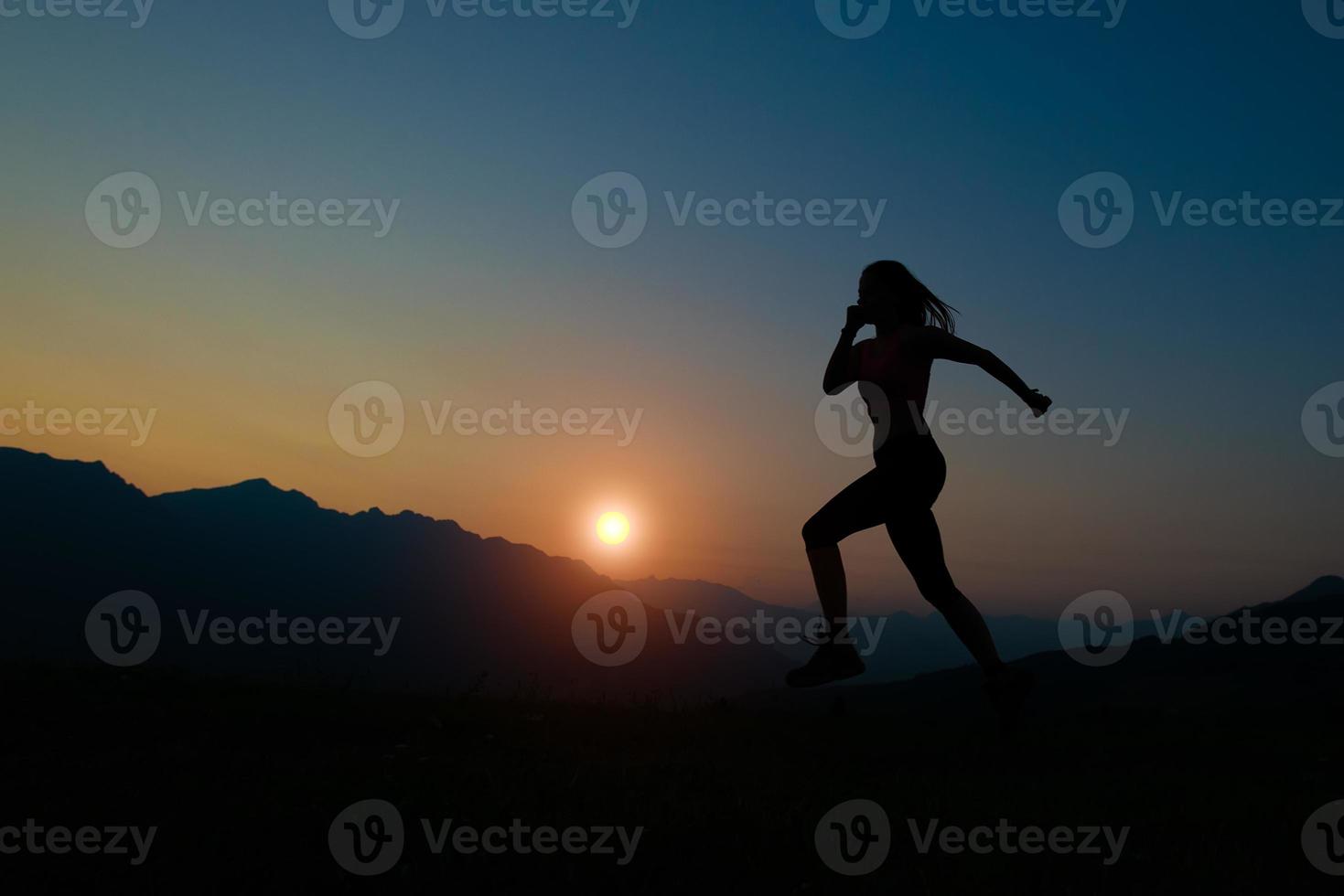 Silhouette of woman running at sunset in the mountains photo