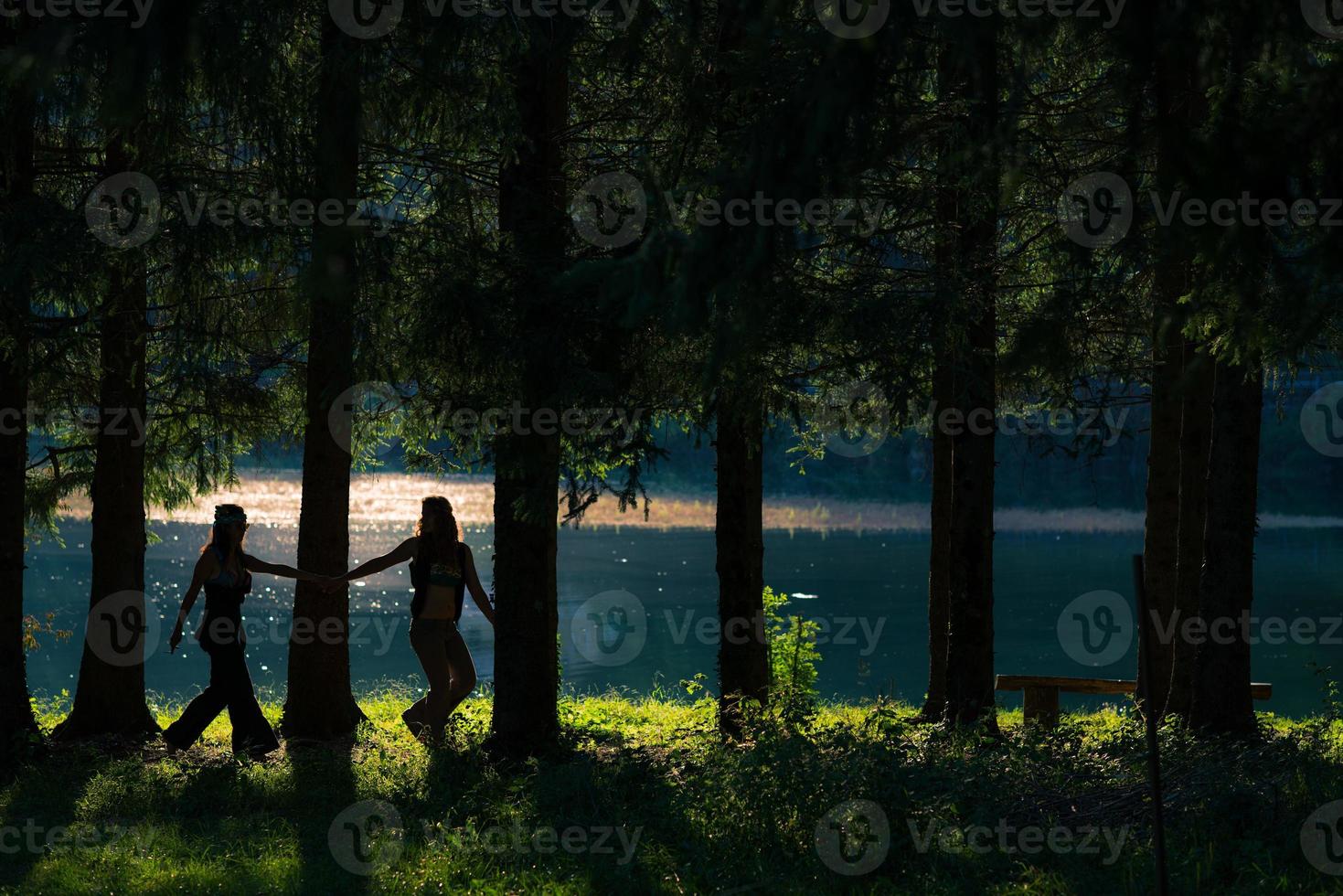 Pretty free hippie girls walking through the woods. Lake view - Vintage effect photo