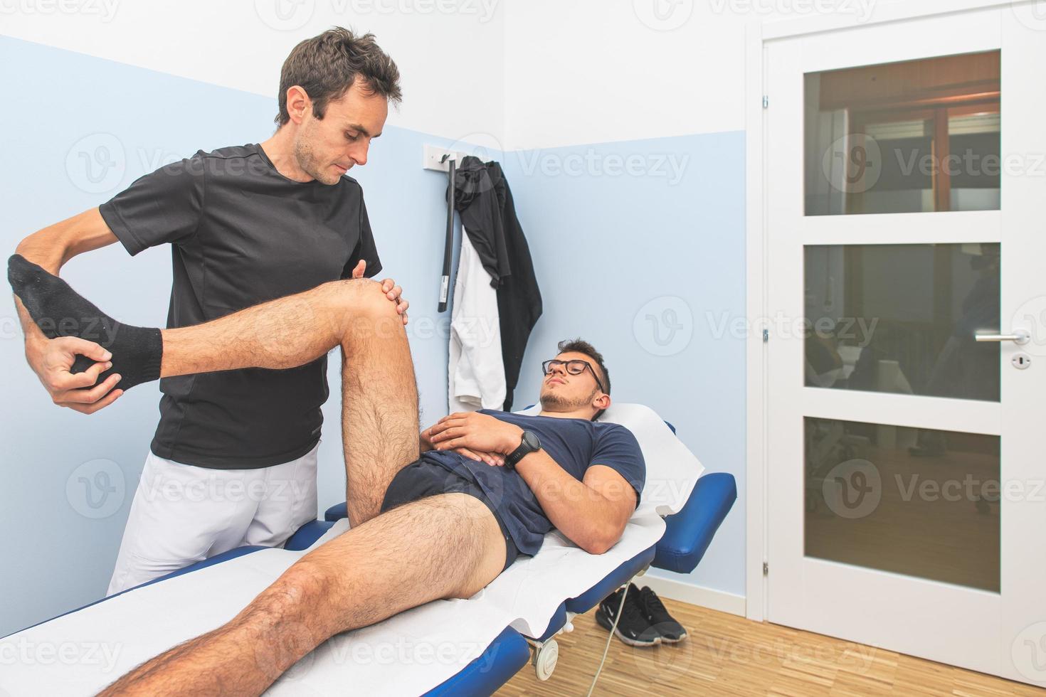 A physical therapist performs. a lower limb mobilization photo