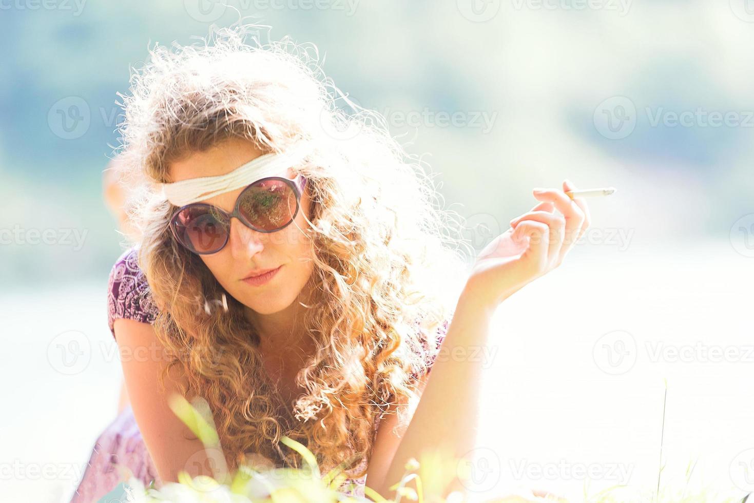 chica hippie bastante libre fumando en la hierba - foto de efecto vintage