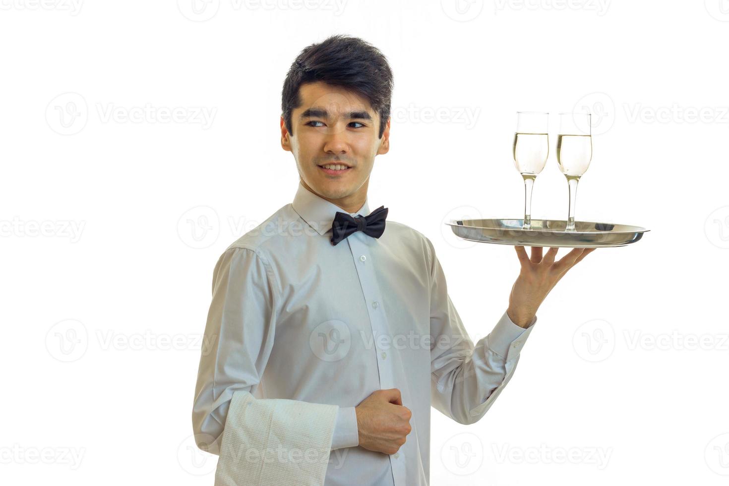 smiling attractive waiter is straight and raised in hand a tray with glasses of wine close-up isolated on white background photo