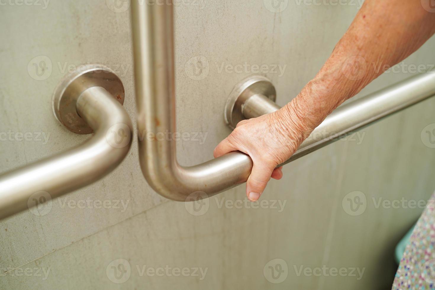 Asian elderly old woman patient use toilet support rail in bathroom, handrail safety grab bar, security in nursing hospital. photo