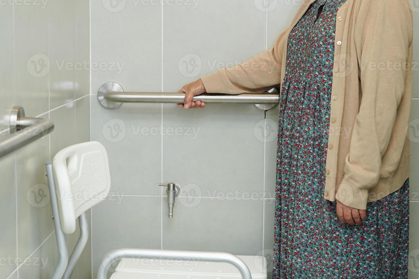 Asian elderly old woman patient use toilet support rail in bathroom, handrail safety grab bar, security in nursing hospital. photo