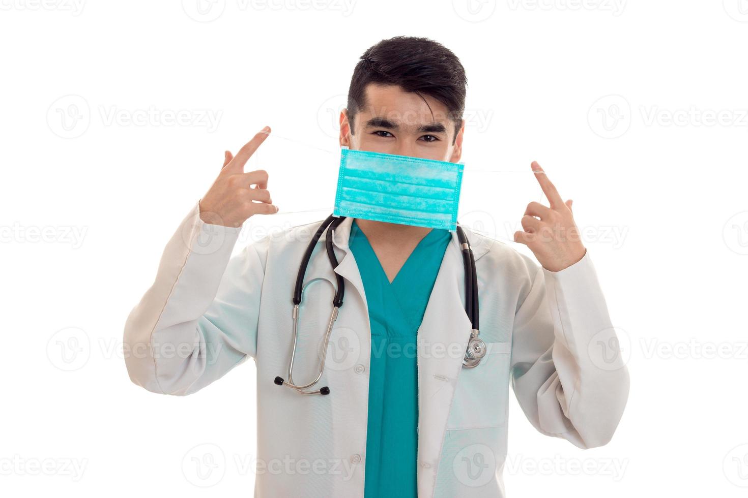 male doctor in uniform and mask with stethoscope posing isolated on white background photo