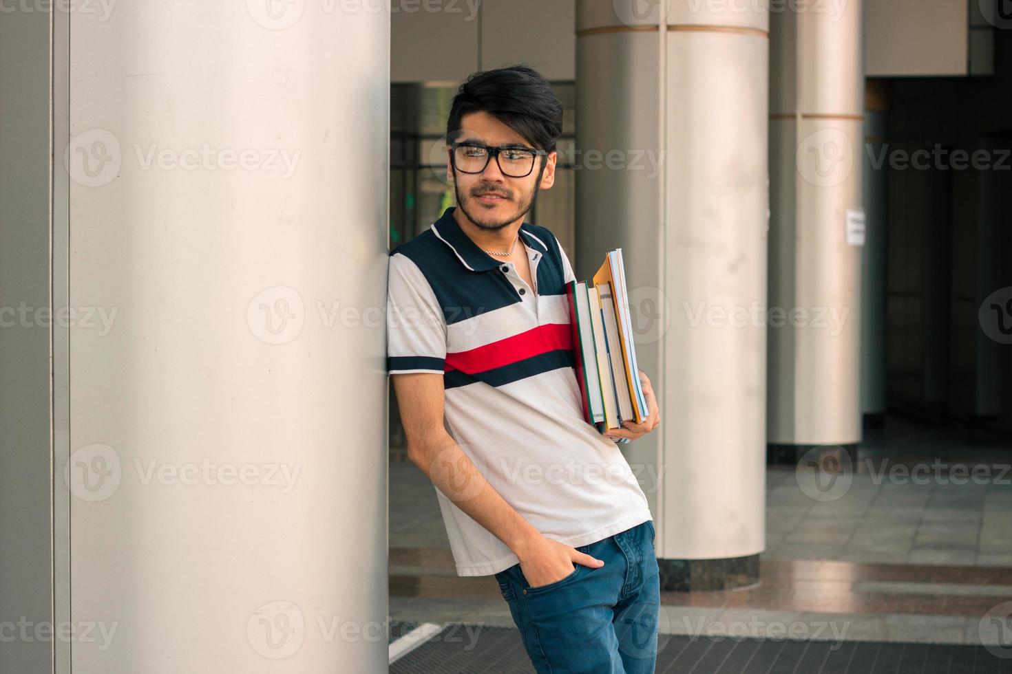 cute guy in a t-shirt stands on the street and keeps on hand book photo