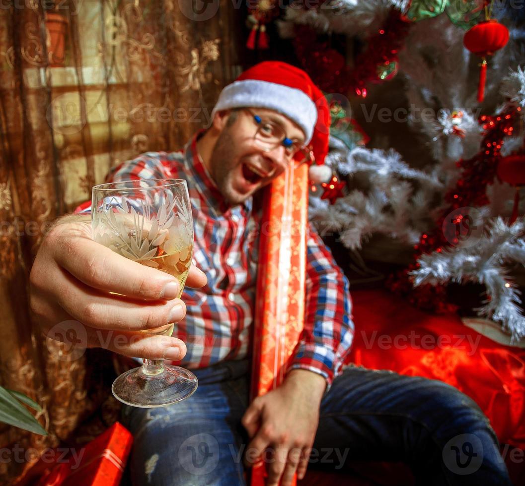 Drunk hipster with glass of champagne under Christmas tree photo