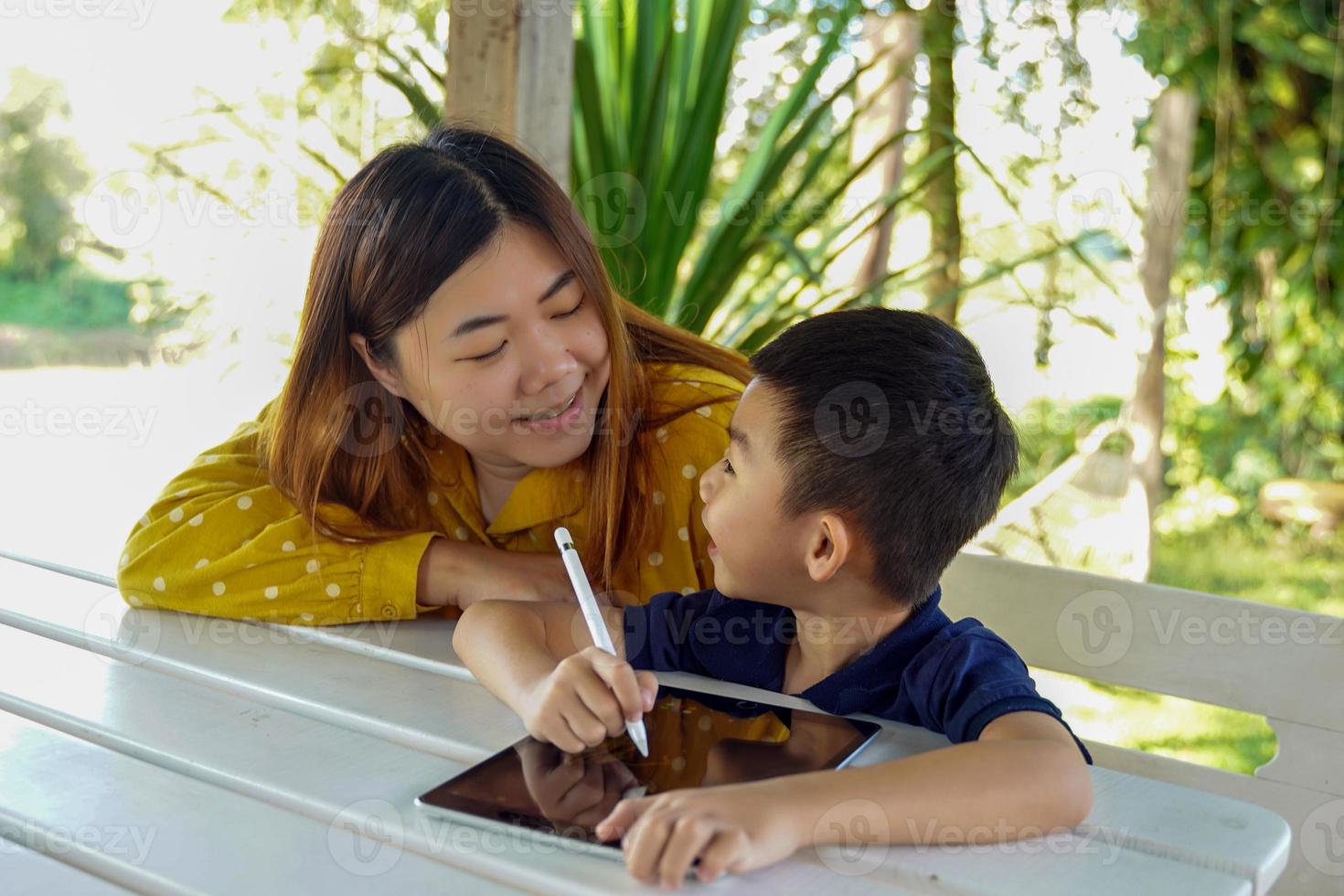 Mother teaches son to use tablet to learn online. Concept adult teaching children, family relations, family, learning outside the classroom, outside activities.soft and selective focus. photo