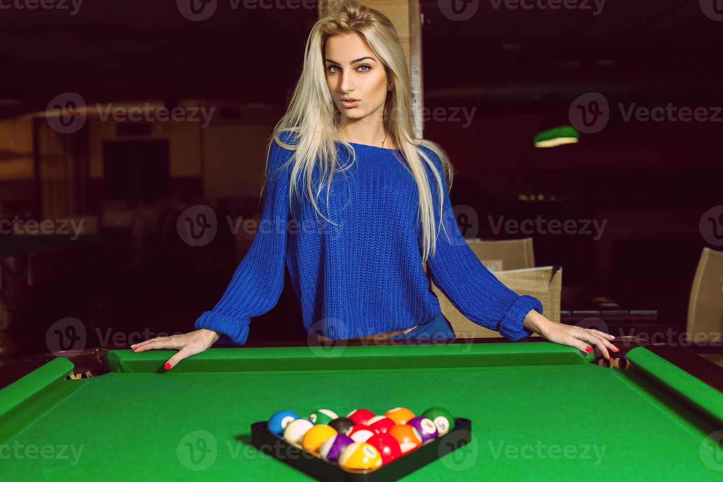 Lovely adult blonde posing near a billiard table with a pyramid of balls photo