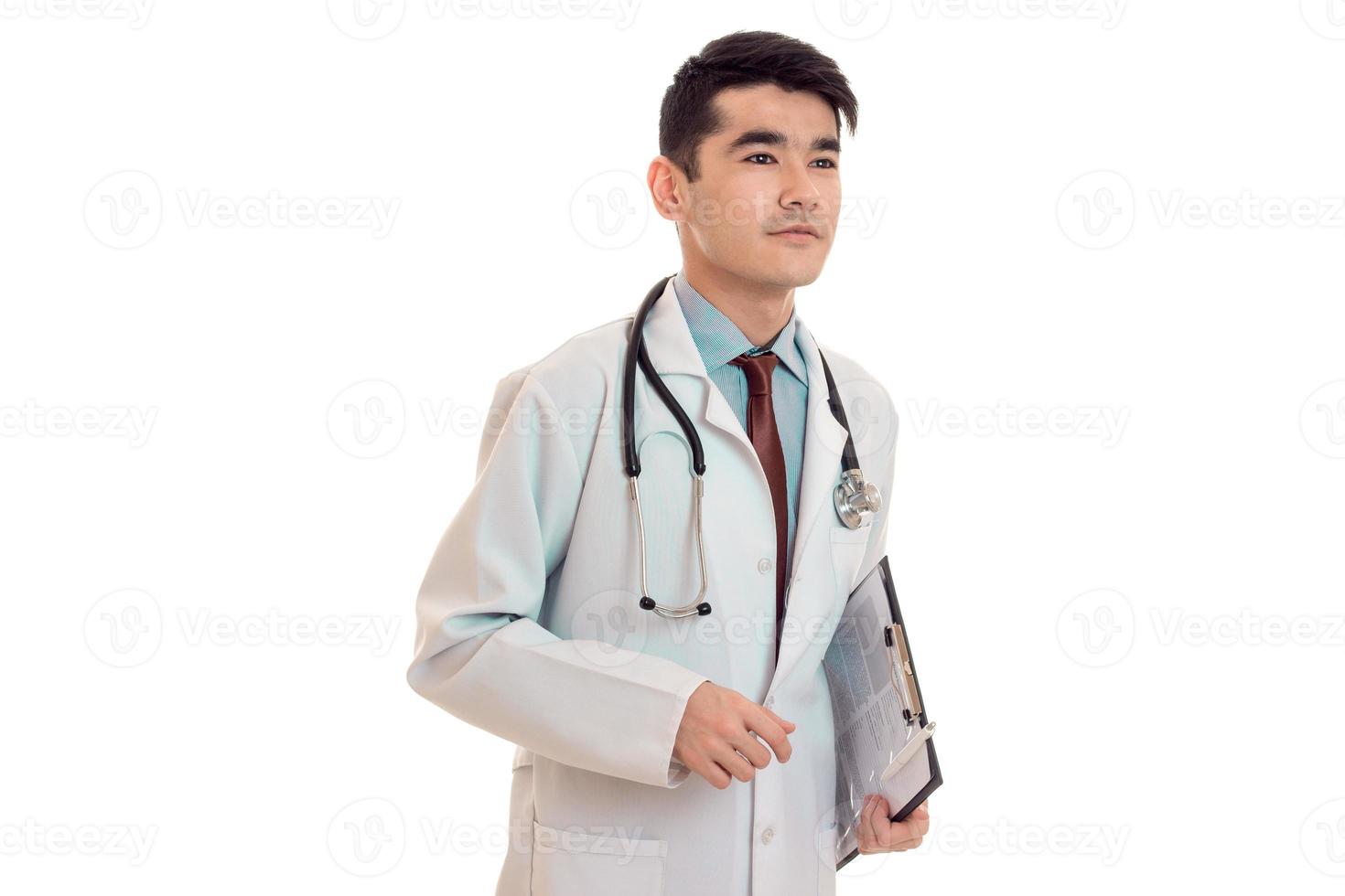 Doctor bastante masculino en estetoscopio uniforme posando aislado sobre fondo blanco. foto