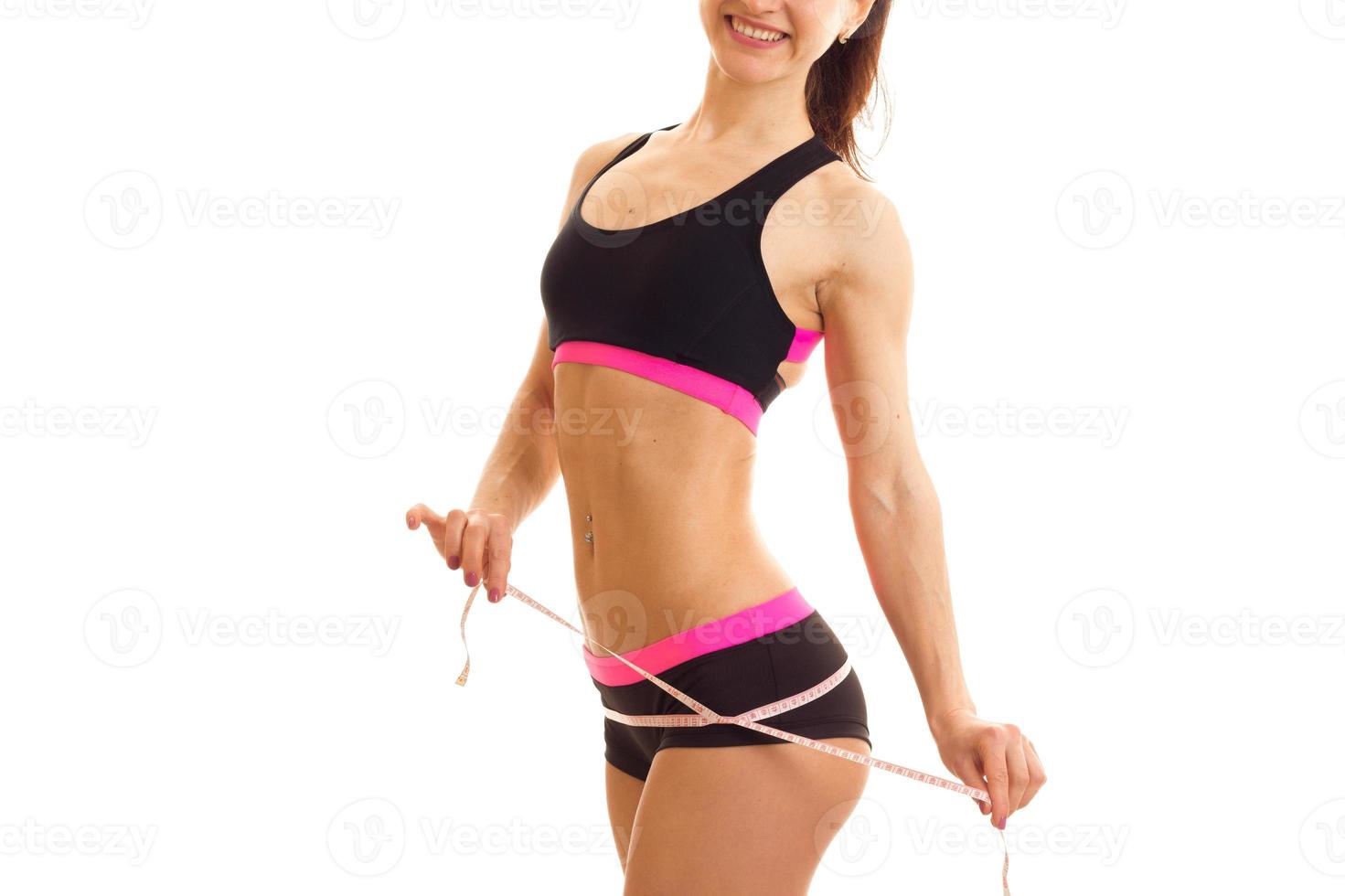 Athletic slim girl in shorts and top measures waist photo