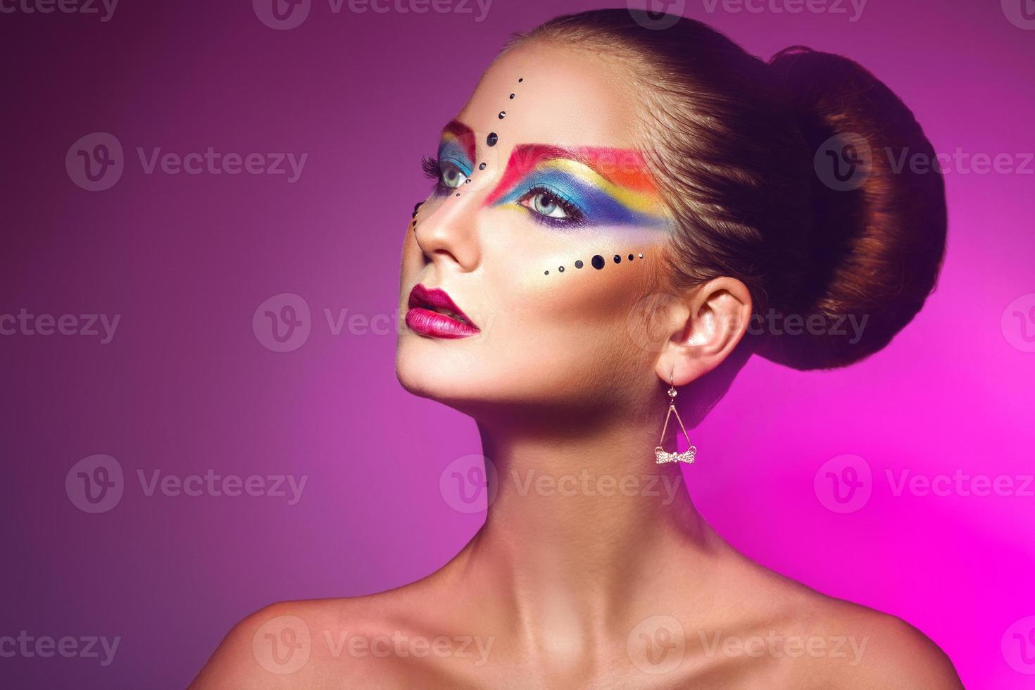 Horizotnal portrait of attractive woman with multicolor make up on purple backgorund photo