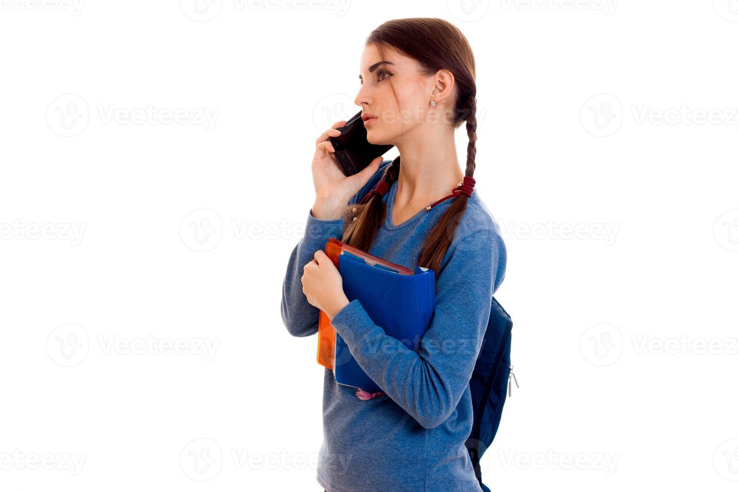 young girl with pigtails is worth turning sideways in a blue jacket and says by phone photo