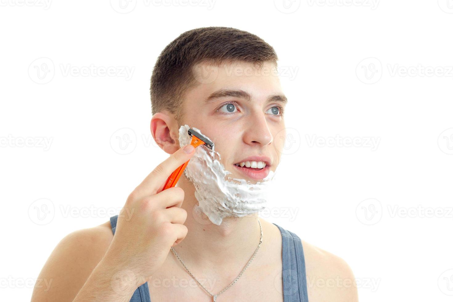 a close-up portrait of young smiling guy with shaving foam on your face and the machine photo