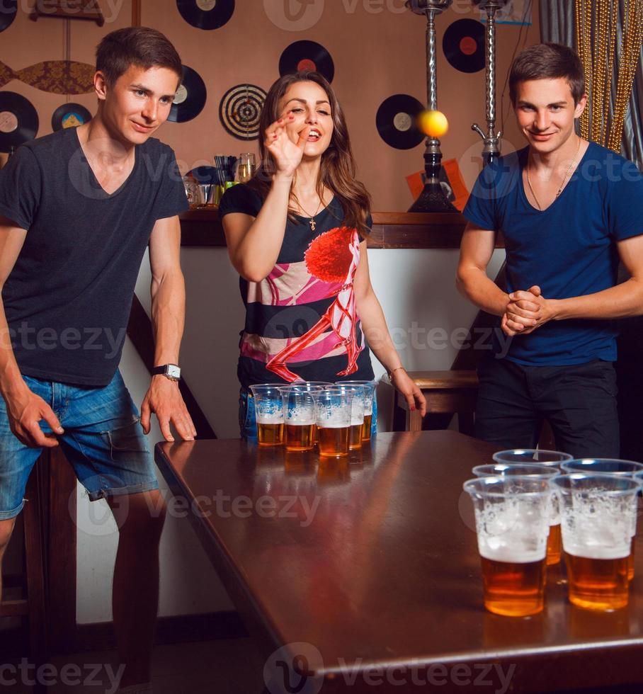 Beautiful brunette girl having fun with twins playing beer pong photo