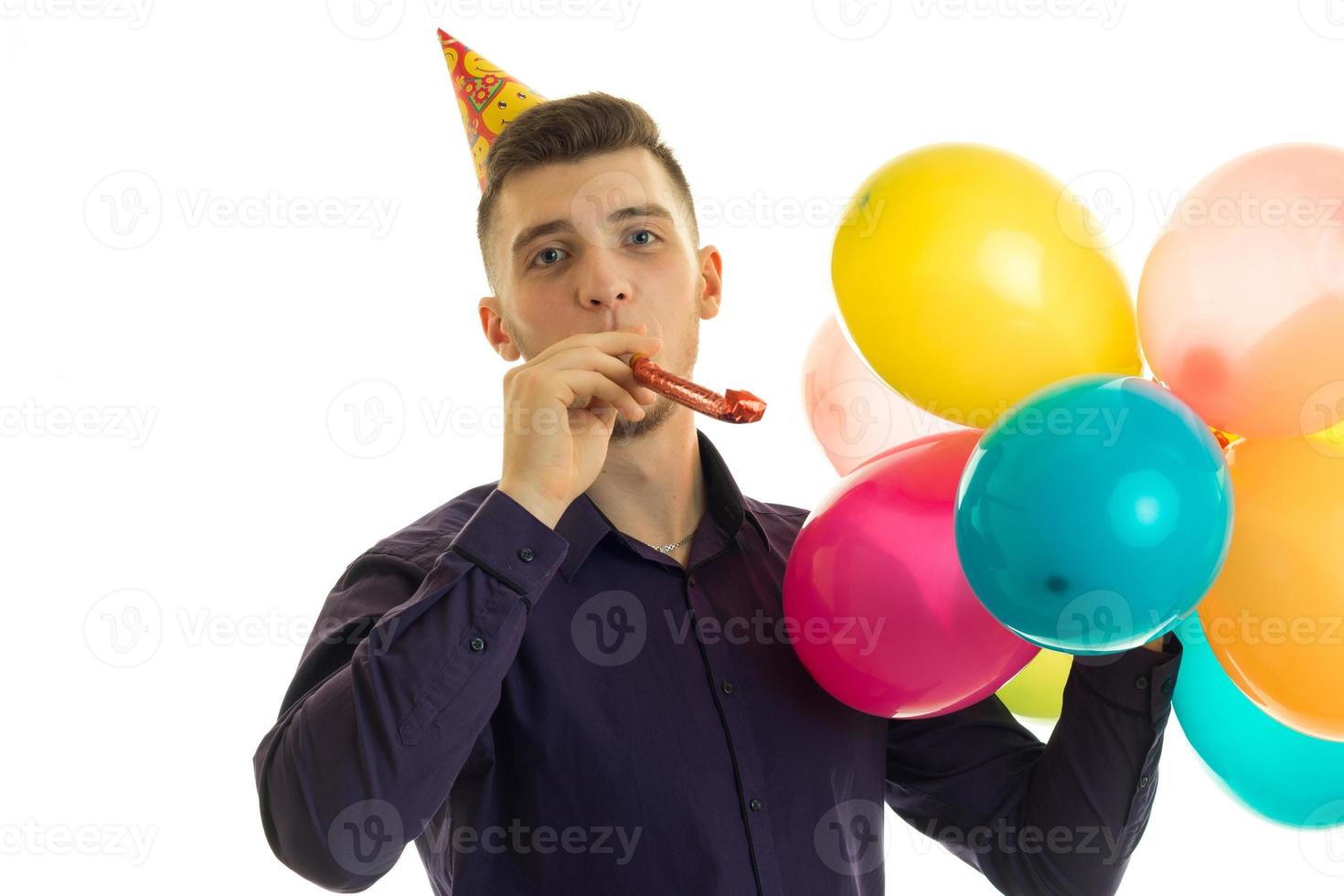 funny cute guy with a cone on his head looking directly holds in his hand and blows balls in dudelku close-up photo