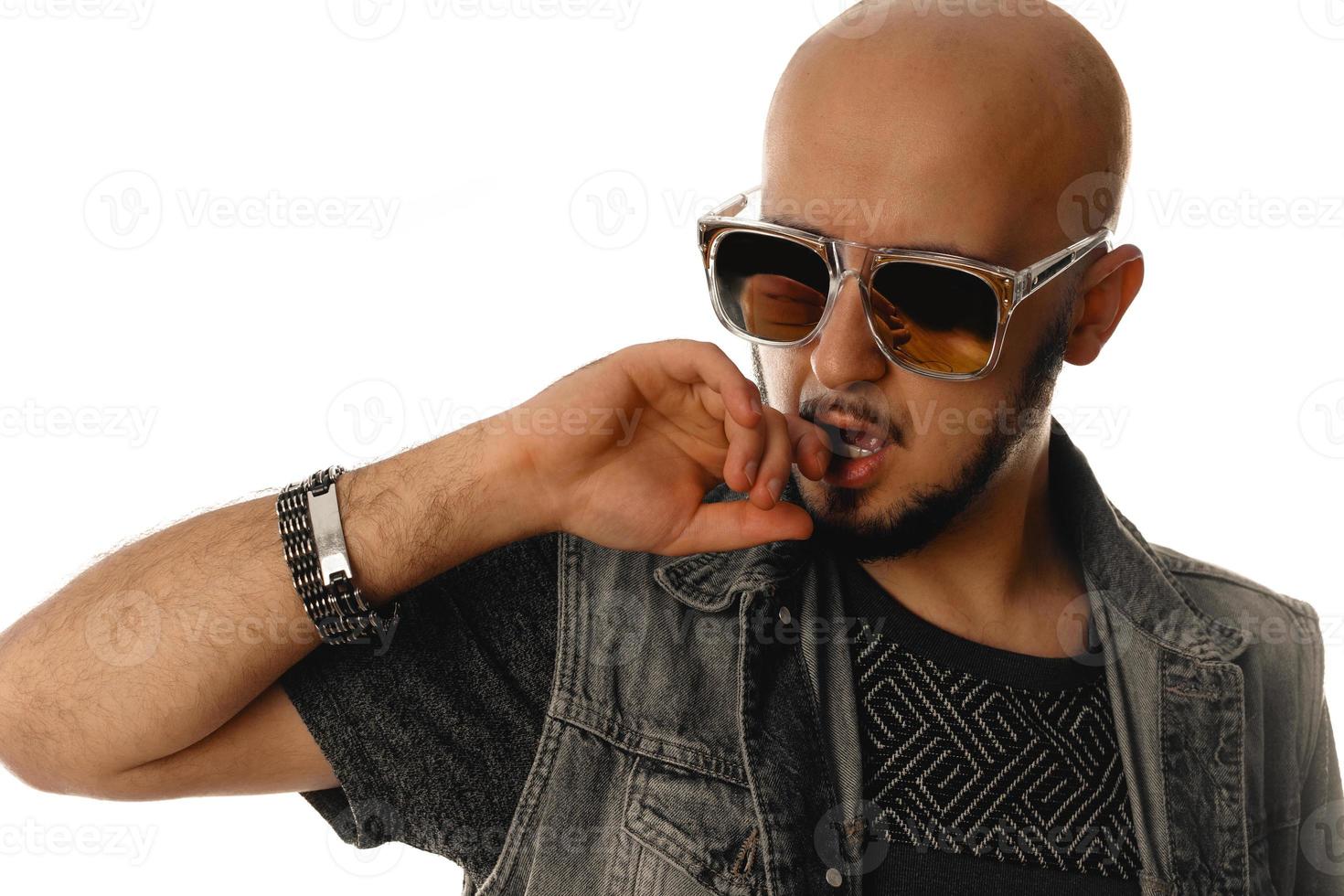 sexual young macho man with hand at his mouth in sunglasses in studio photo