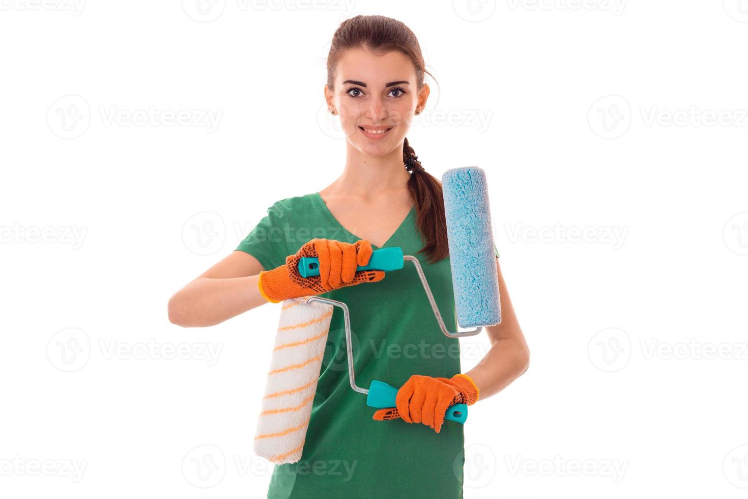 Charming young slim builder girl makes renovations with paint roller isolated on white background photo