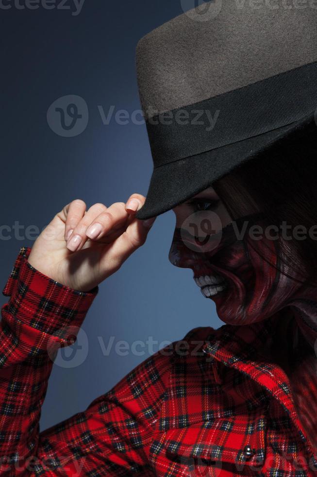 Profile portrait of woman in halloween art on face and hat photo