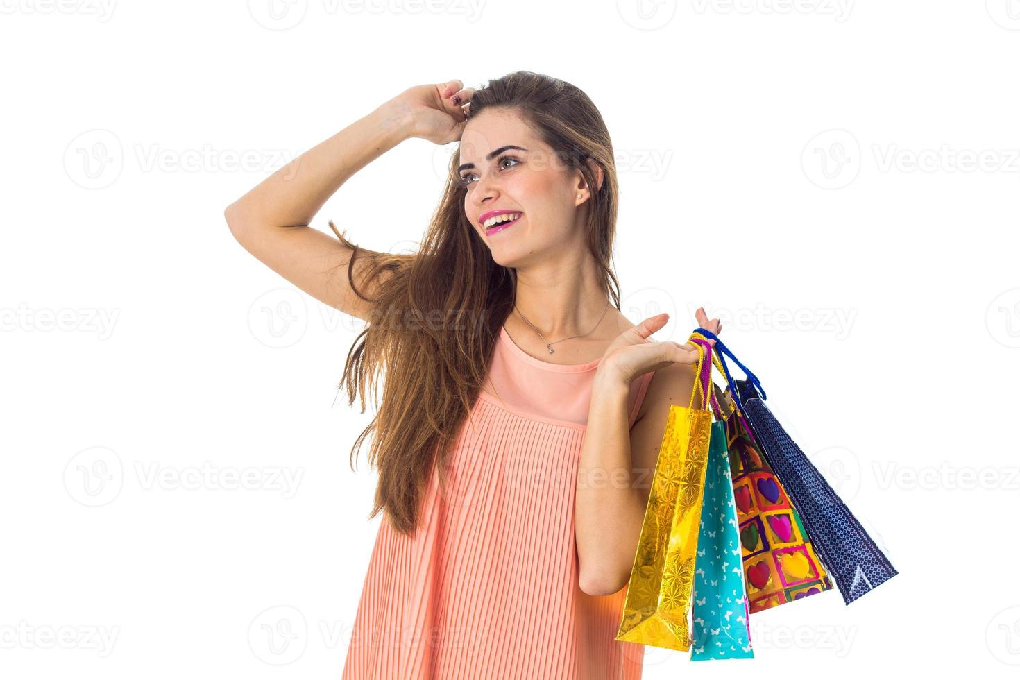 joyful girl looks away and keeps the color packages from stores isolated on white background photo