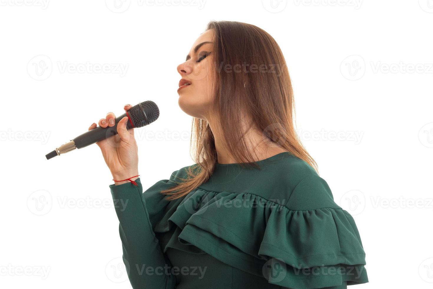 Sensual young girl in green dress sings song in microphone photo