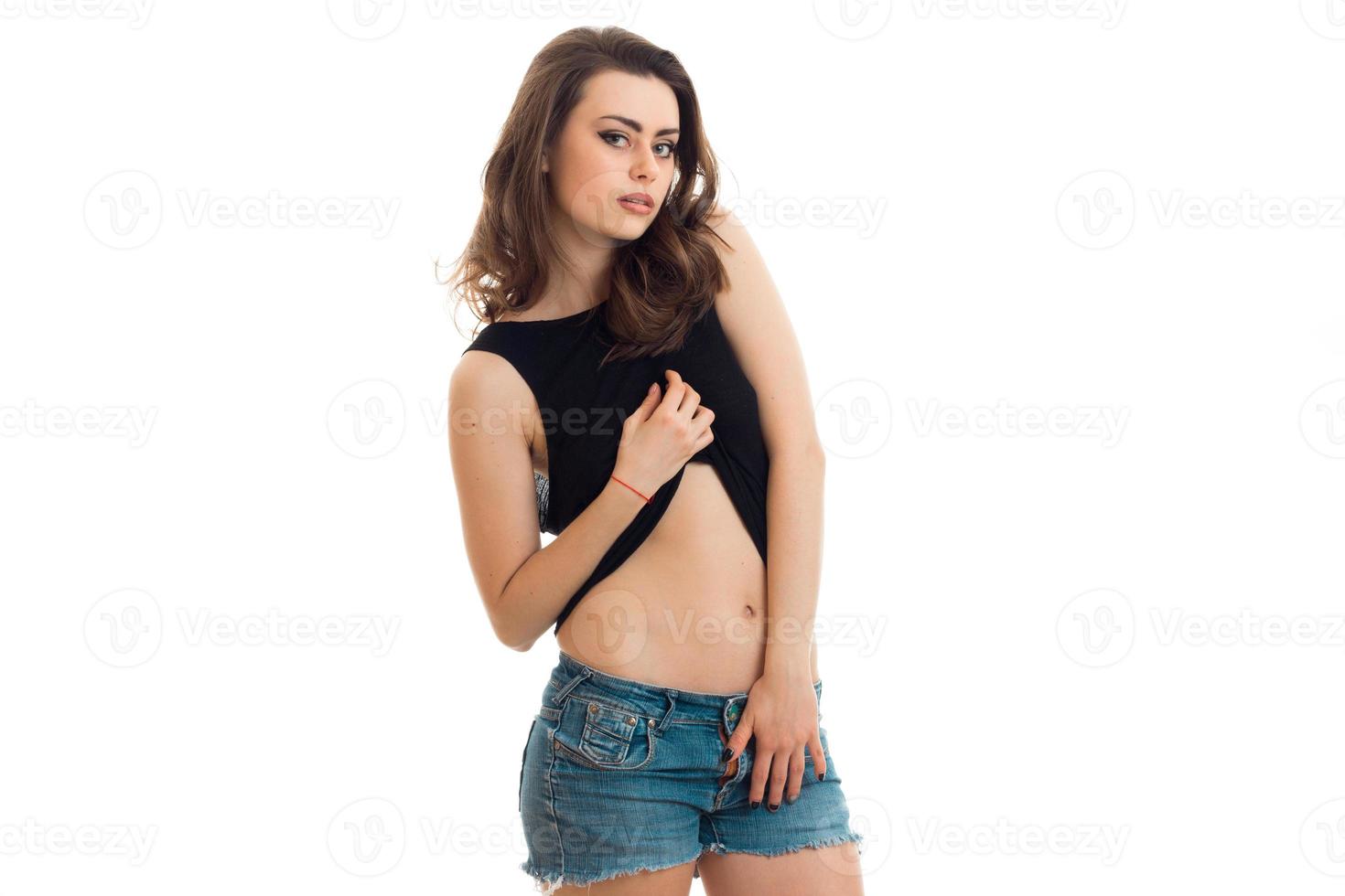 young beautiful girl in denim shorts and a t-shirt with a hand raised looking at camera photo