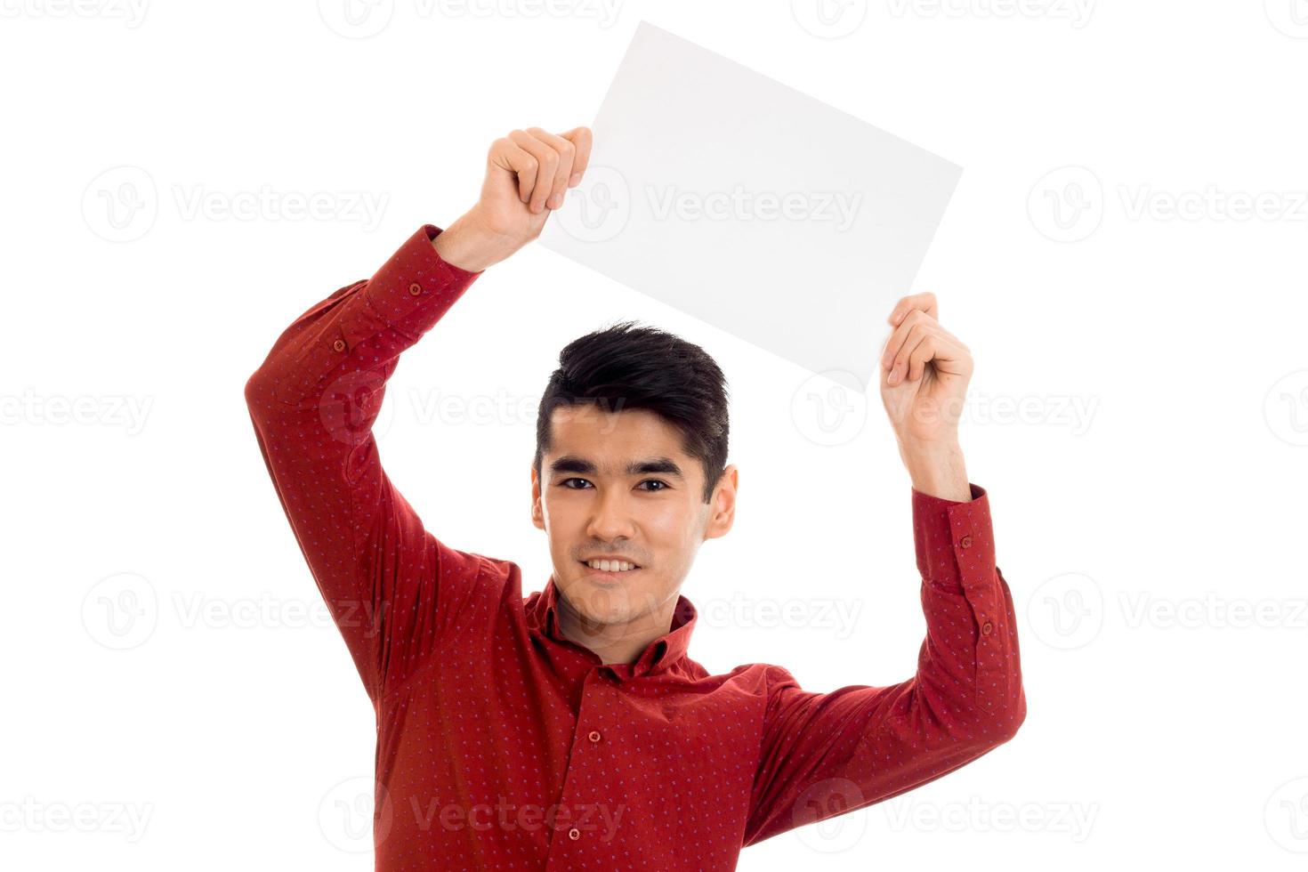 young cheerful brunette man in red t-shirt posing with white placard isolate on  background photo