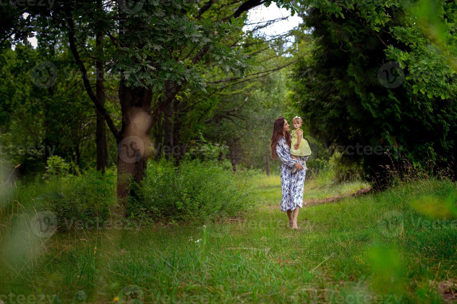 beautiful young woman walks carrying little baby girl at the garden photo