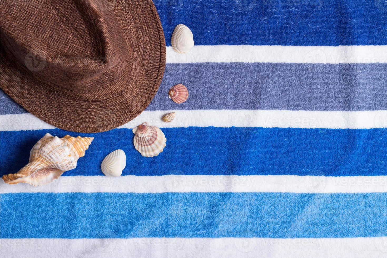 A summer holiday composition on a beach towel with seashells and a hat. photo