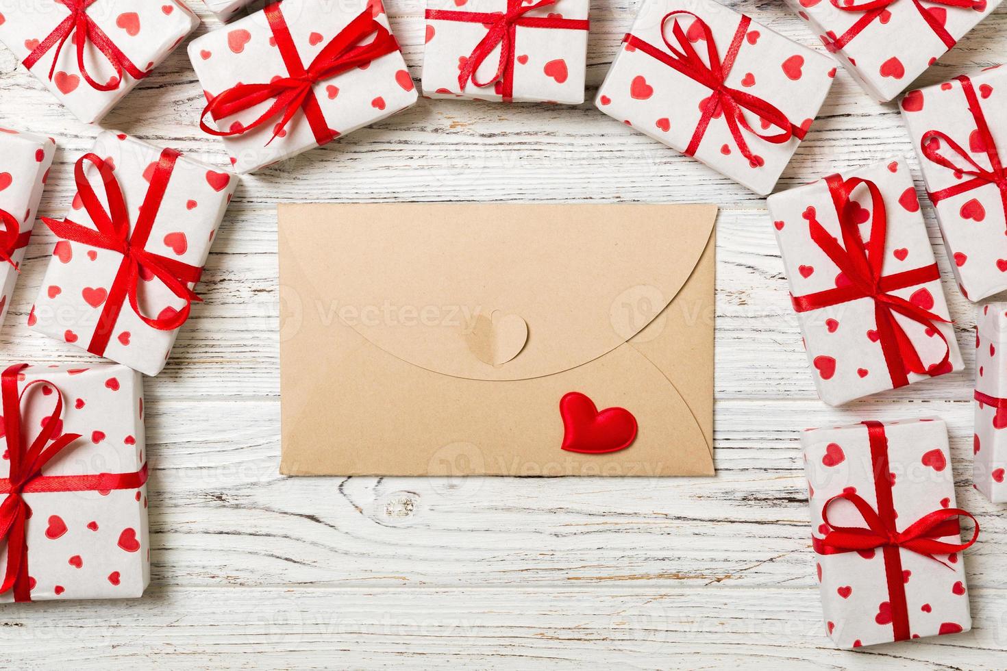 correo de sobre con corazón rojo y caja de regalo sobre fondo de madera. diseño de concepto de tarjeta de San Valentín, amor o saludo de boda foto