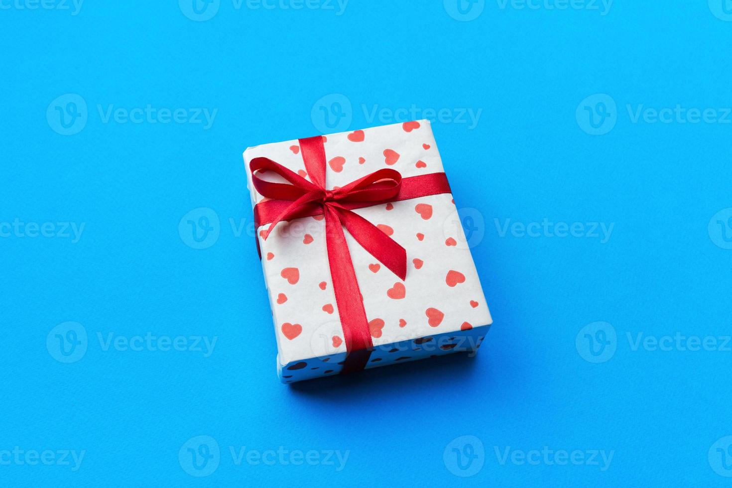 Background with gift box and hearts on blue Background. Top view with copy space for text photo