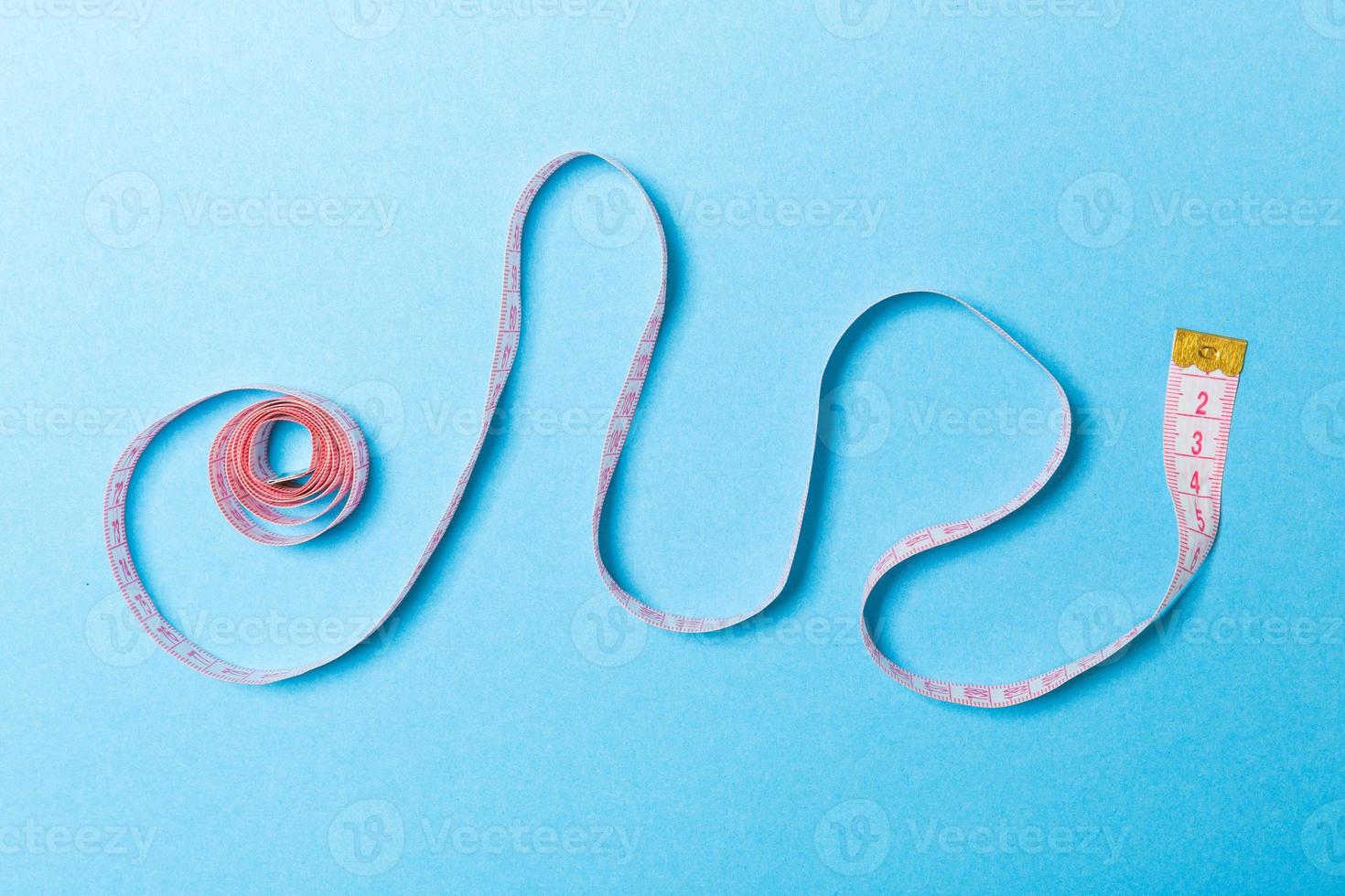 Creative idea of spiral tape measure on blue background. Sewing concept photo