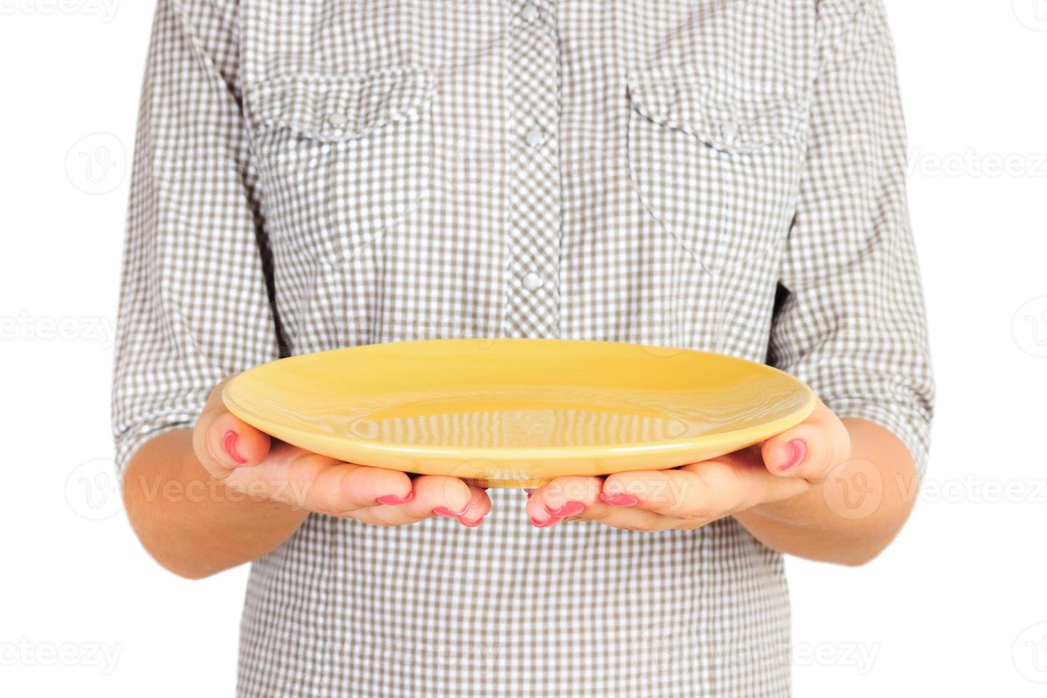 girl in the plaid shirt is holding an empty round yellow plate in front of her. woman hand hold empty dish for you desing. perspective view, isolated on white background photo