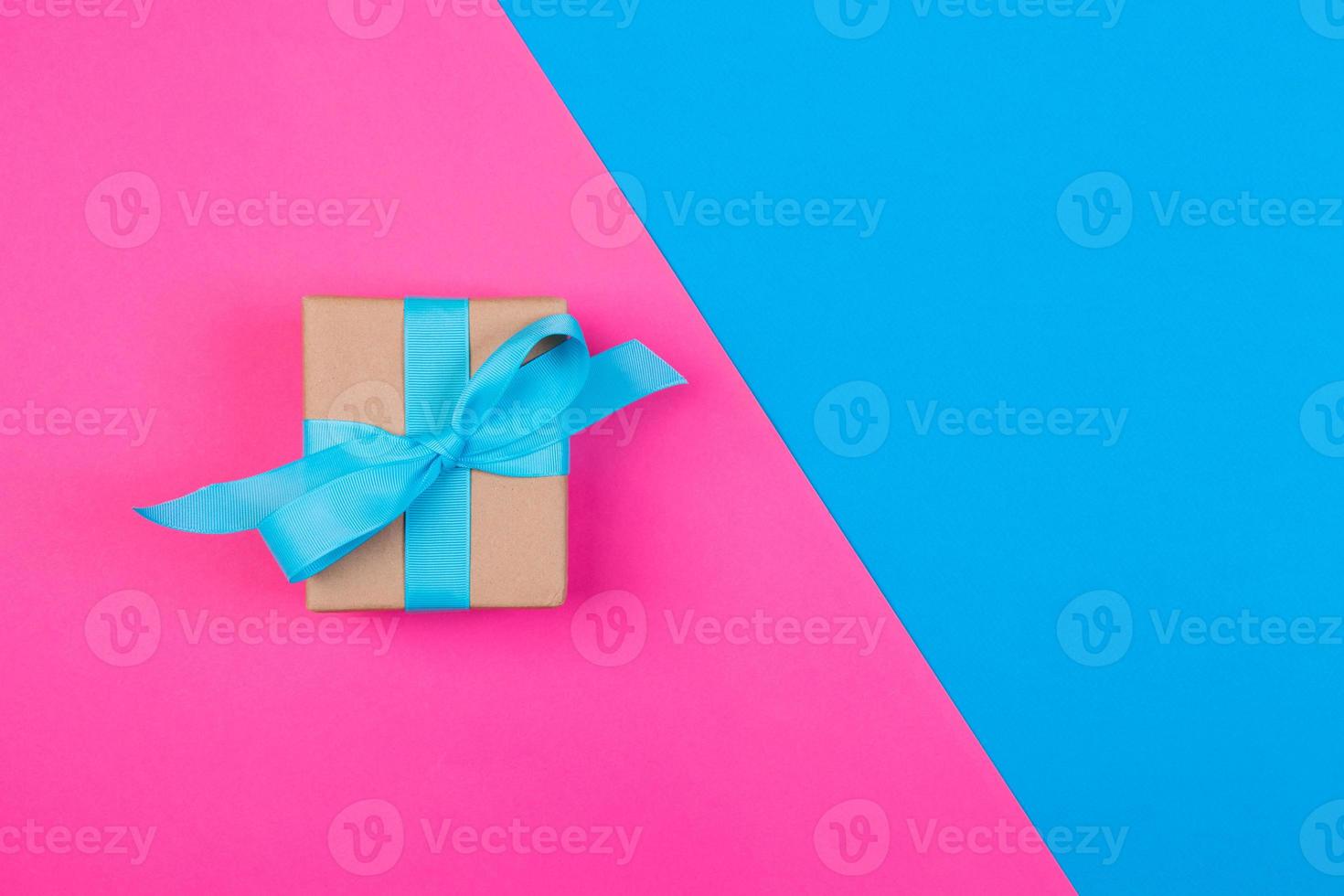 gift wrapped and decorated with blue bow on colored background with copy space. Flat lay, top view photo