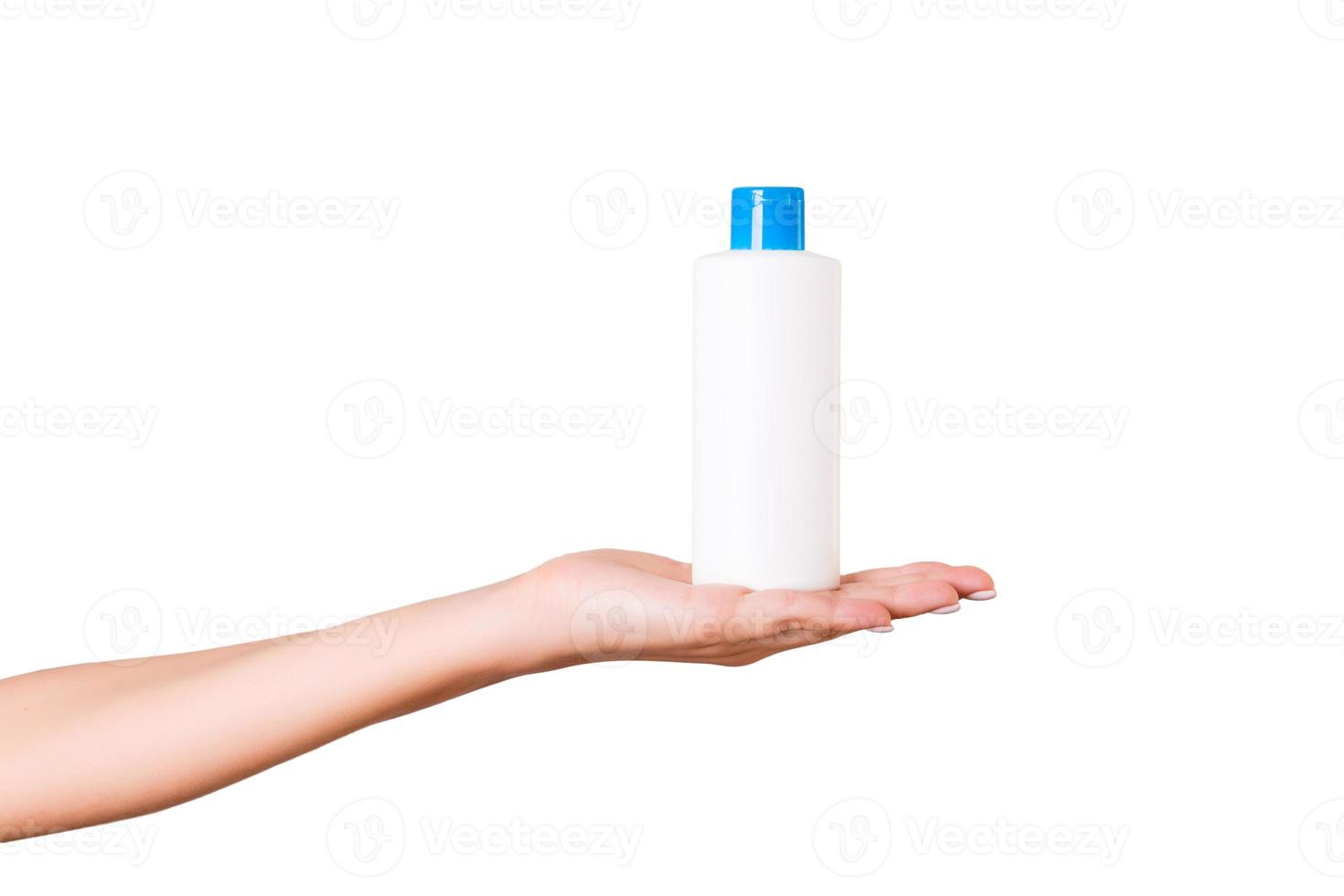 Female hand holding cream bottle of lotion isolated. Girl give tube cosmetic products on white background photo