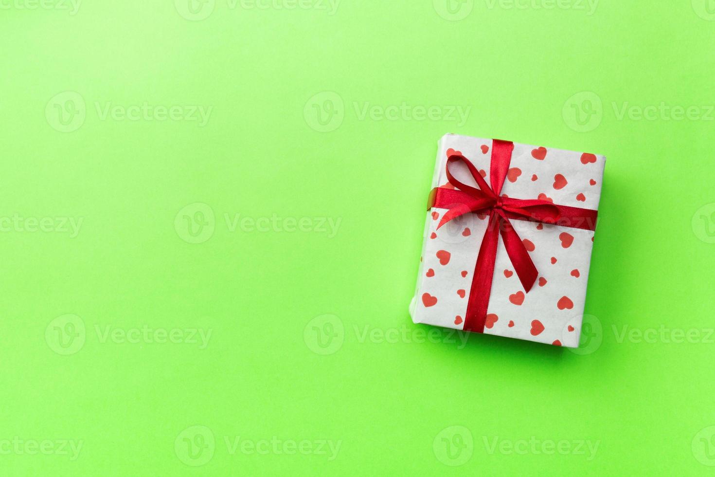 Background with gift box and hearts on green Background. Top view with copy space for text photo