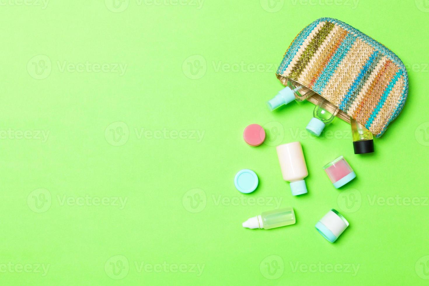 bolso cosmético de mujer con un conjunto de productos de belleza y crema para el cuidado del cuerpo sobre fondo verde con espacio de copia para su diseño foto