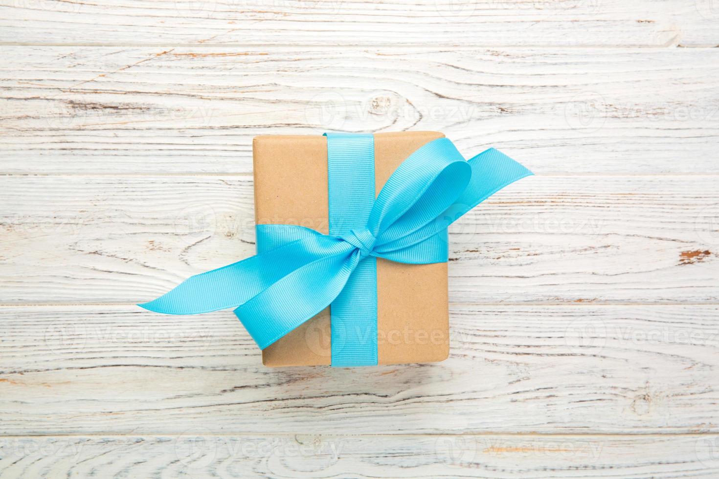 recycled paper gift box with Blue ribbon on old wooden white background.Top view photo