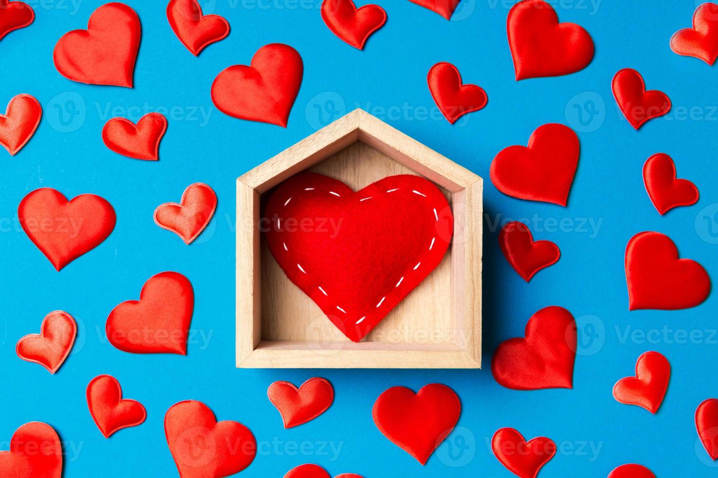 Close up of red heart in a wooden house decorated with small hearts on colorful background. Valentine's day. Home sweet home concept photo