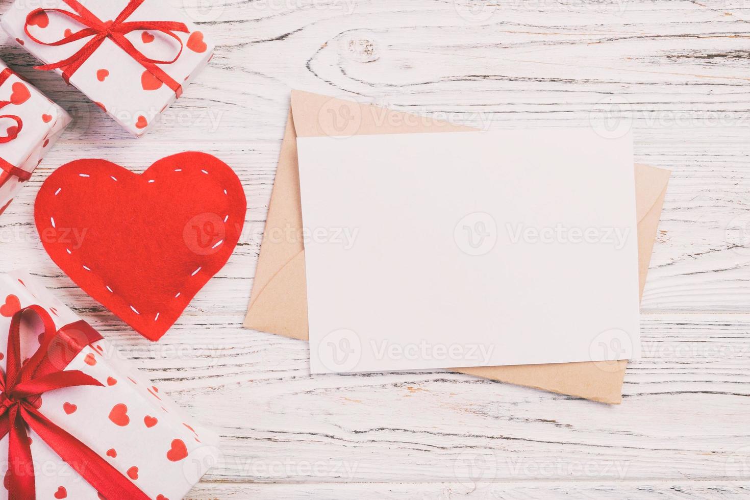 correo de sobre con corazón rojo y caja de regalo sobre fondo blanco de madera. tarjeta de san valentín, amor o concepto de saludo de boda foto