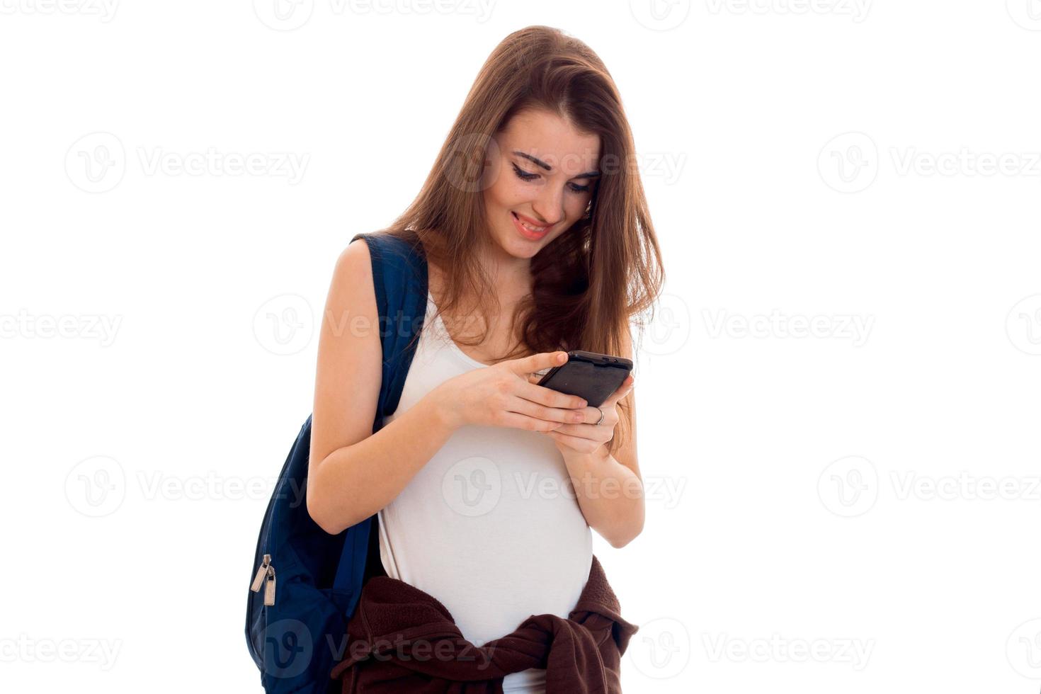 beauty young brunette student girl with backpack with mobile phone isolated on white background photo