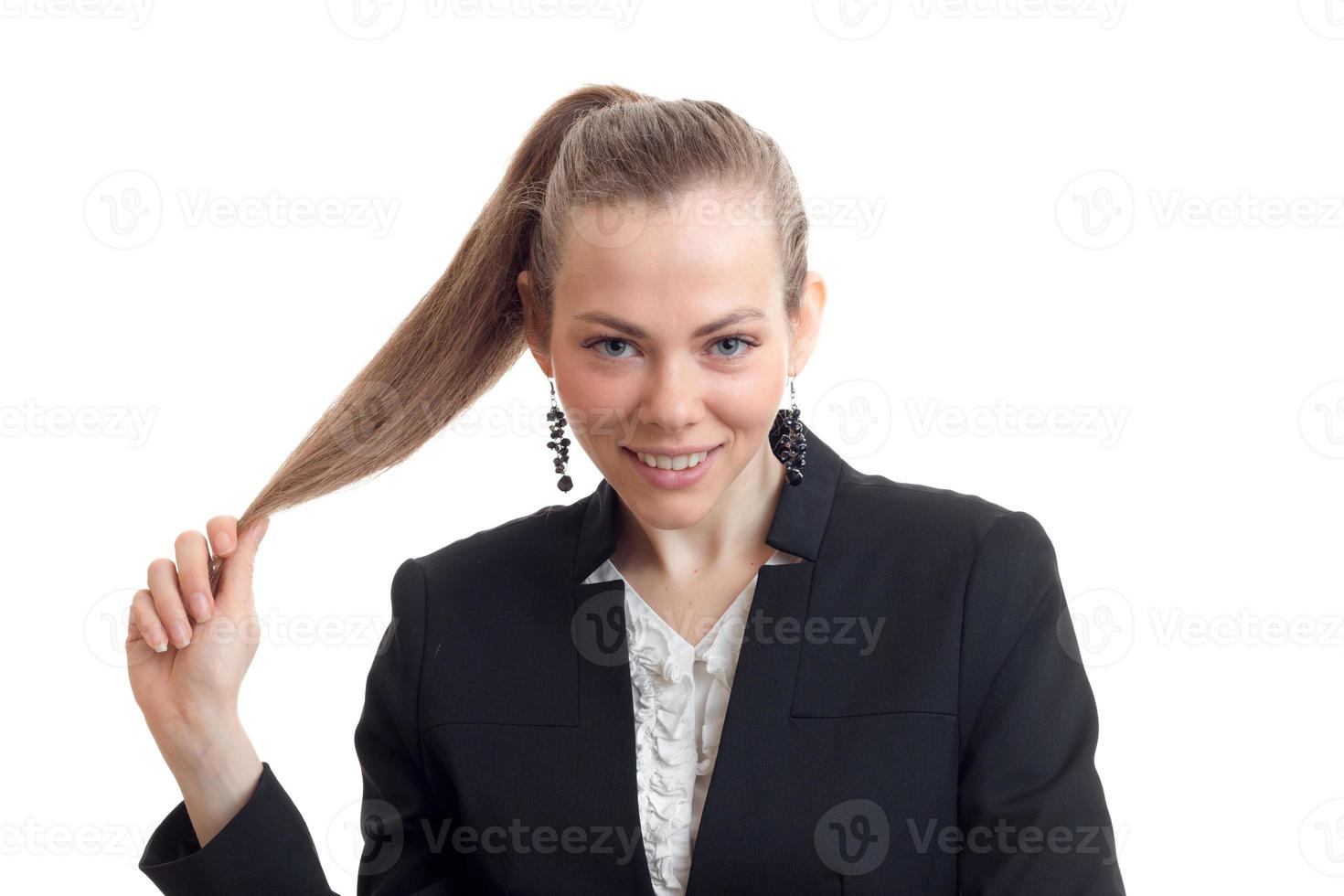 Portrait of sexual young blonde who is smiling looks into the camera and holds hand ponytail photo