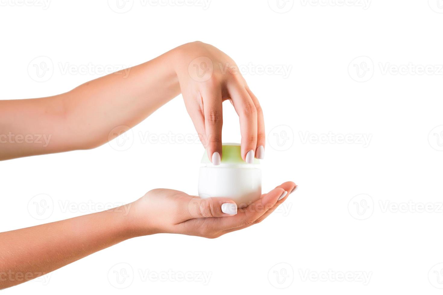 mano femenina sosteniendo una botella de crema de loción aislada. Chica abriendo tarro de productos cosméticos sobre fondo blanco. foto