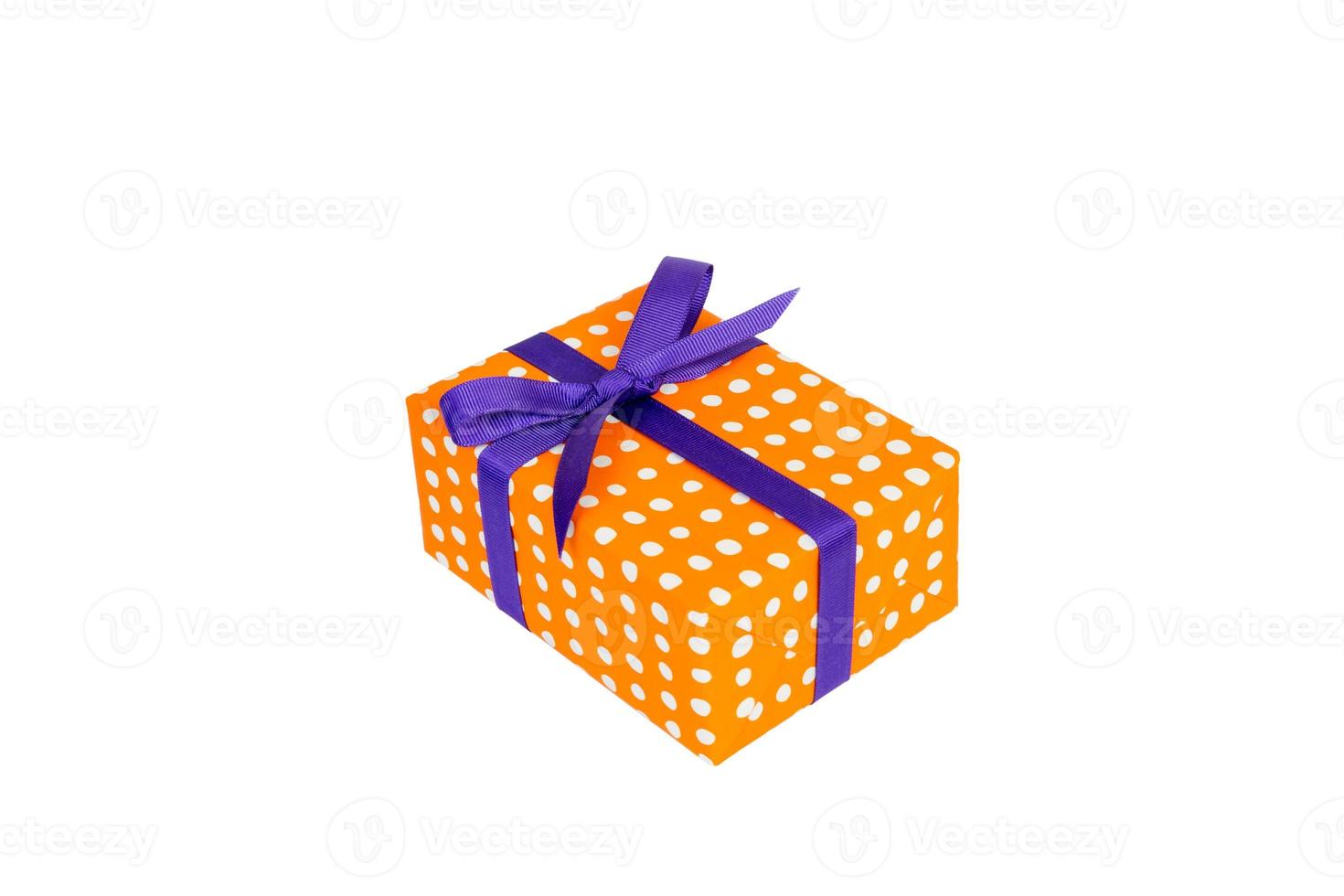 Christmas or other holiday handmade present in orange paper with purple ribbon. Isolated on white background, top view. thanksgiving Gift box concept photo
